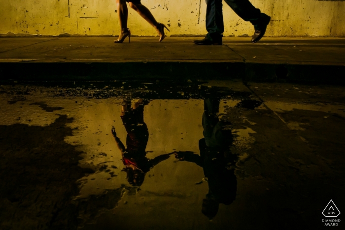 California couple walking by the water puddle and reflected in a creative engagement picture