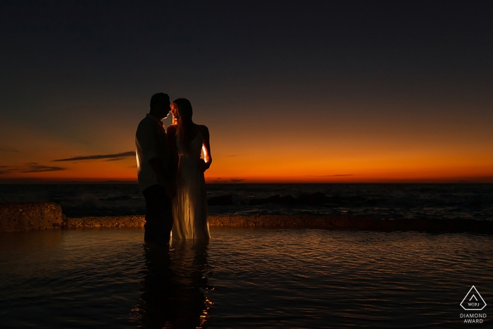 Un couple californien debout et éclairé avant le coucher du soleil orange