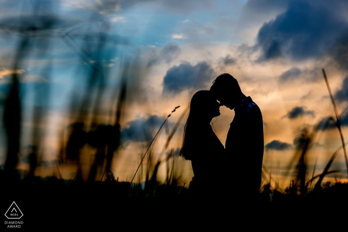 Budapest couple stands in an embrace, their heads touching at sunset