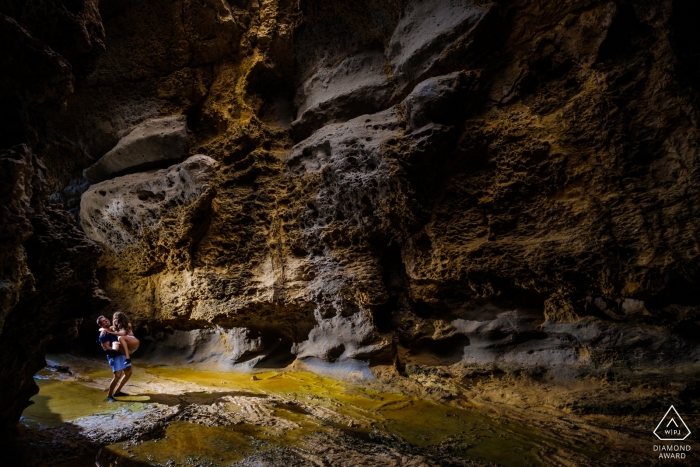 An Alicante engaged couple pictured amongst the rough tall rock walls of the cave