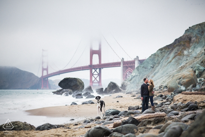 Pareja de California abrazándose en la playa rocosa cerca del puente Golden Gate