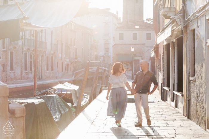 Casal de noivos de Venezia andando de mãos dadas no cenário de gôndolas