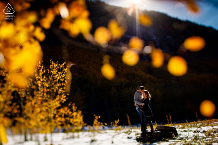 Das verlobte Paar aus Colorado umarmt sich unter den Herbstblättern von Summit Co