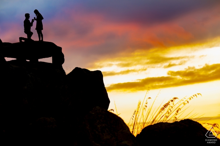 The Trapani couple is silhouetted against a vibrant sky of blue, purple, yellow and green hues