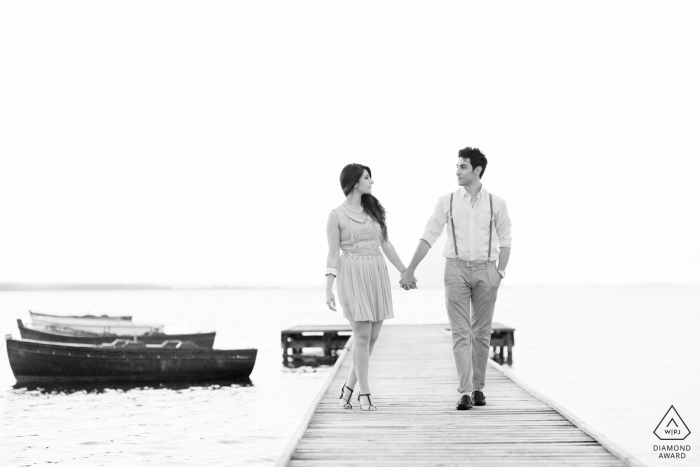 black and white image of two lovers walking on a jetty by the sea | Trapani, Sicily Portraits | hand in hand