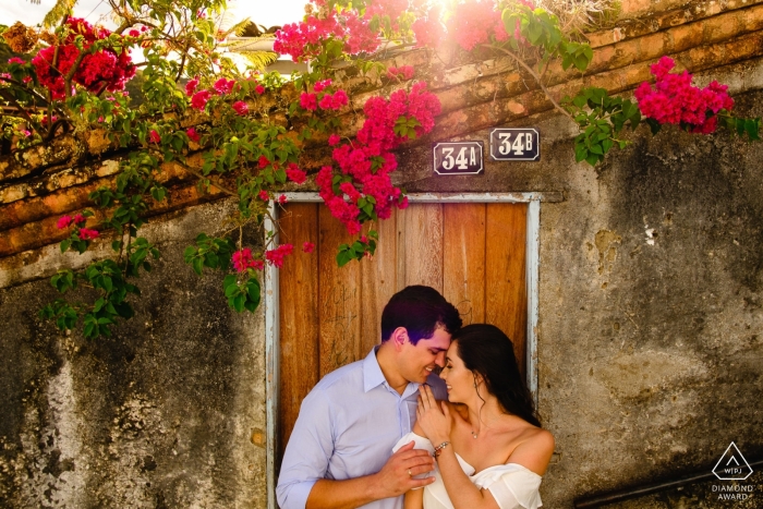 Séance photo d'engagement de Minas Gerais avec un couple au soleil avec des bâtiments et des fleurs