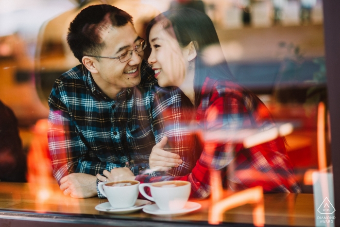 A newly engaged San Francisco couple enjoying a moment together inside a coffee shop as the city is reflected in the class before them