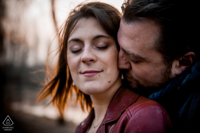 France engagement portrait with a woman closing her eyes as she is kissed on the neck by her fiancé