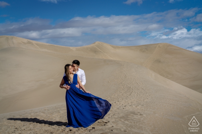 Un couple s'embrasse au sommet des dunes de sable pour leur portrait de fiançailles à Death Valley