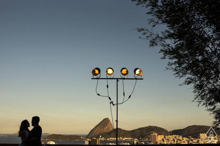Engaged couple are silhouetted as they enjoy the view of Rio de Janeiro, Brasil from their lookout session