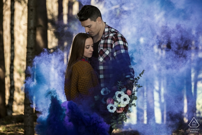 Foto de compromiso italiano humo azul en el bosque con el ramo de flores