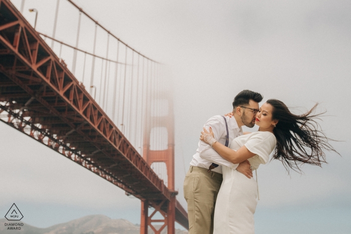 Photo: <a href="https://www.wpja.com/photos/diamond-award-top-wedding-engagement-photographer/2439636"> Raymond Nguyen - Sacramento en Californie Séance de portraits de fiançailles à San Francisco au Golden Gate Bridge | le vent lui souffle les cheveux alors que le brouillard obscurcit le pont