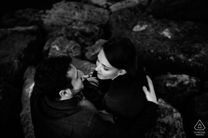 The couple posed for their black and white portrait on the sea with the beach rocks in the background, their all black clothing adding to the heavy contrast and drama of the images Noli (Savona), Liguria, Italia - Black and white Couple portrait on the Ligurian sea