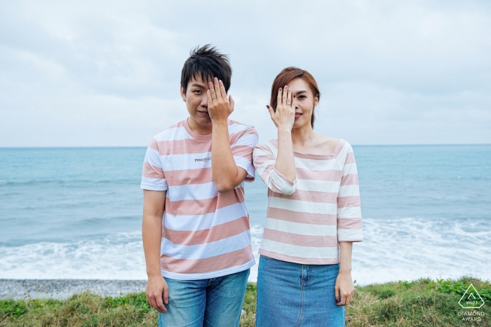 Taiwan, Hualien symmetrical engagement portrait at the beach | they each cover one eye with their hands