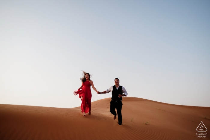 Deserto de Maleiha, sessão de retrato de noivado de Dubai - aventura de deserto na areia com um vestido vermelho