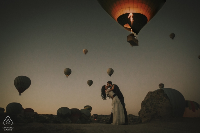 Portraits de fiançailles en Cappadoce d'un couple s'embrassant sous des montgolfières