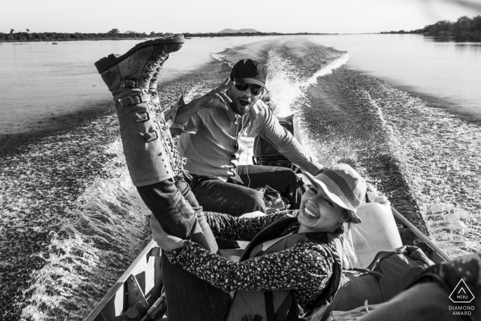 Engagement photos on a small motorboat show her tall boots on display in the air as they enjoy a romantic ride Pre-wedding portraits in Pantanal, Mato Grosso do Sul, Brasil | engagement Photos on a small motorboat