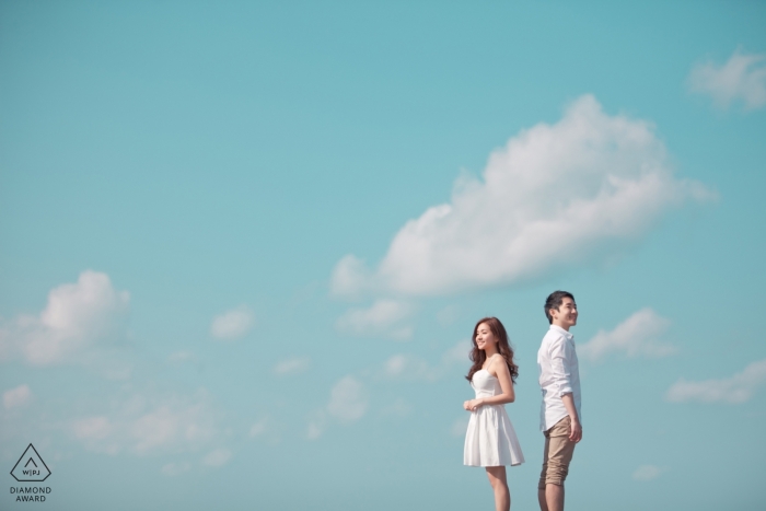 Jeju, Korea couple shooting pre-wedding portraits with a blue sky and clouds