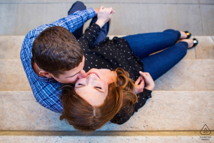 Un couple s'assoit sur les marches pour la séance de fiançailles de Manhattan à New York