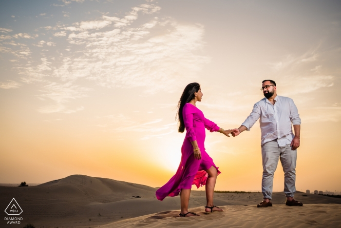 Photographe de mariage émirati, prise de conscience de couples tenant par la main au coucher de soleil à Dubaï dans le désert