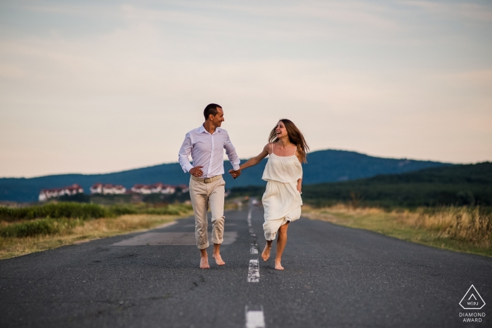 Portraits de fiançailles à Sozopol, Bulgarie - Un couple en cours d'exécution en plein milieu de la route