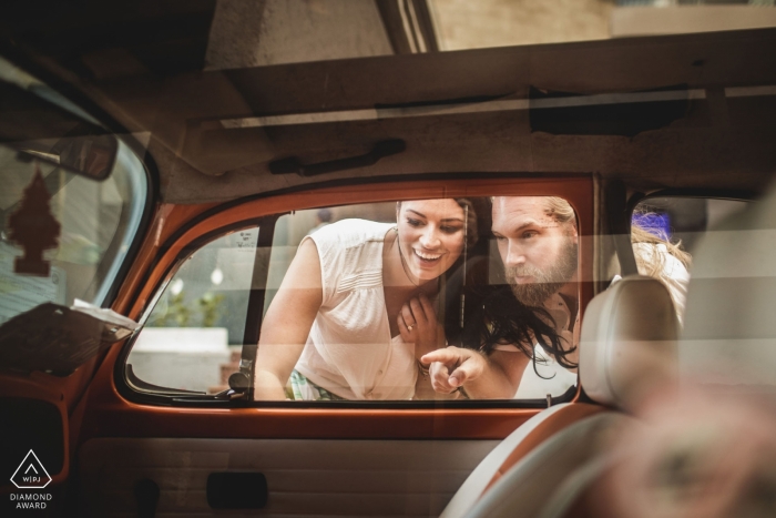 Sesión fotográfica de compromiso en Playa del Carmen | la pareja mira en la ventana de un auto antiguo y pregunta: ¿Dónde están las llaves?