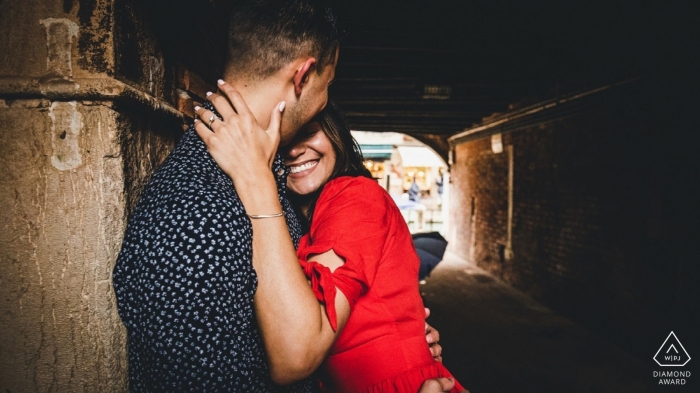 Engagement photo session of a young couple holding each other in a tunnel in Venice. 