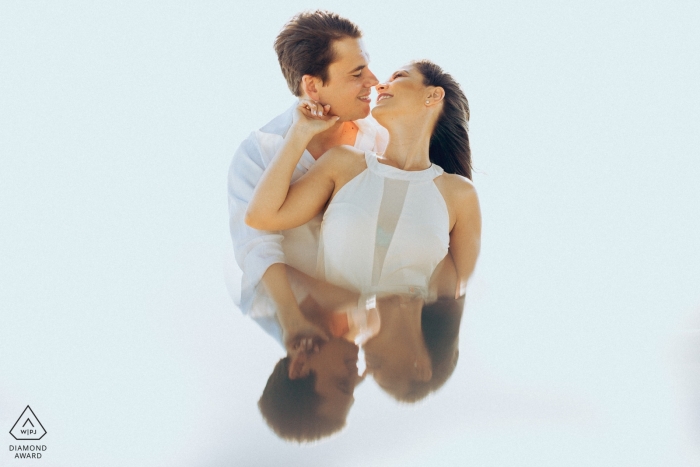 Engagement portrait of the bride and groom holding each other and reflected in Plataforma de Osório.