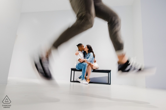 Artehouse, Washington, D.C engagement portrait with a videographer jumping while the couple is kissing on a bench 