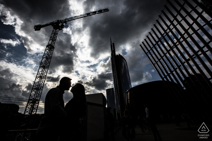 Photo by: <a href="https://www.wpja.com/photos/diamond-award-top-wedding-engagement-photographer/2460976">Massimiliano Beccati - Milano Milano Black and white engagement photo of a couple silhouetted beneath a construction crane in Milan, Italy.