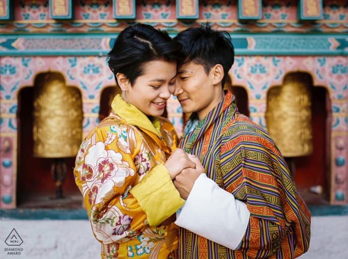 Foto de compromiso de una pareja de pie frente a un templo en Thimphu, Bhután.