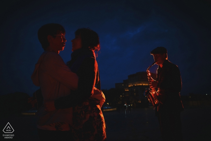 Sessão de Retrato Valleta Malta - Um casal aprecia a música de um músico de rua durante sua sessão de noivado em Malta