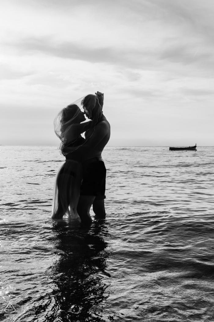 En esta sesión de compromiso, una foto en blanco y negro de Amalfi, Italia, captura a la pareja que está de rodillas en las olas del océano