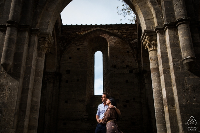 Photo by: <a href="https://www.wpja.com/photos/diamond-award-top-wedding-engagement-photographer/2472376">Filippo Ciampoli - Siena Siena Abbazia di San Galgano engagement portrait of a couple under the arch