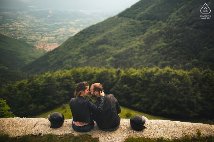 Photo by: <a href="https://www.wpja.com/photos/diamond-award-top-wedding-engagement-photographer/2472411">Paolo Ferrera - Alvito Frosinone Parco Nazionale d'Abruzzo engagement photo shoot as the couple sits on a ledge overlooking a forest below