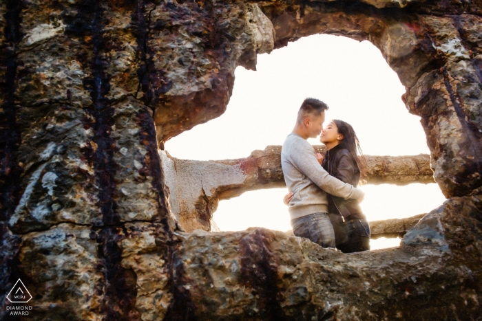 Foto door: <a href="https://www.wpja.com/photos/diamond-award-top-wedding-engagement-photographer/2475001"> Chris Shum - Sunnyvale, Californië De fotograaf gluurt door een onderbreking in de concrete muur om het paar te vangen dat in deze het verlovingsportretspruit van San Francisco omhelst