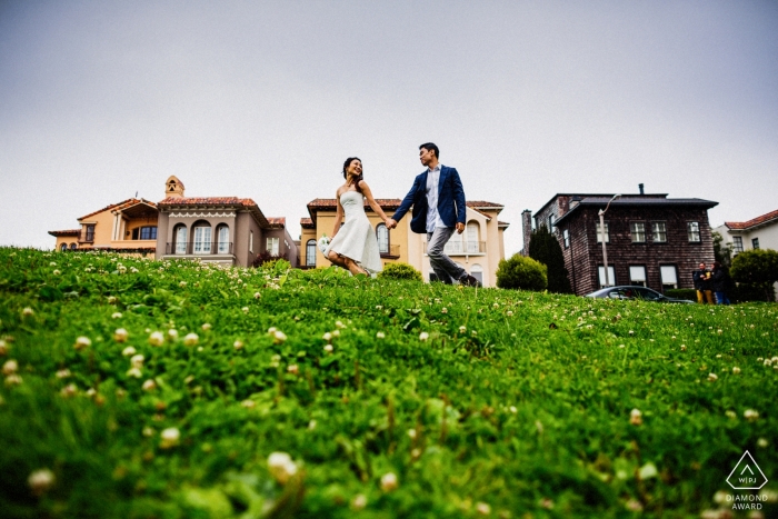 Fotografía de compromiso de San Francisco: la pareja se toma de las manos mientras pasean por un patio cubierto de hierba