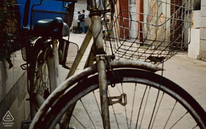 Guangdong: en esta sesión previa al retrato de la boda, el fotógrafo captura a la pareja abrazándose en la distancia mientras una bicicleta descansa en primer plano.