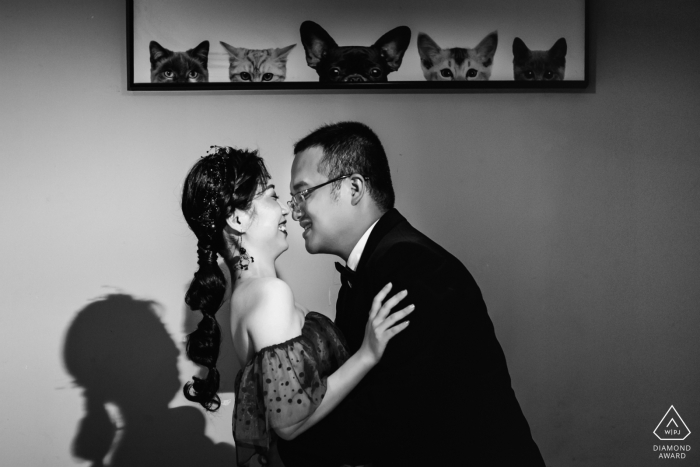 Fujian, China- the happy couple is seen embracing under a picture of a dog and cats in this black and white pre-wedding portrait