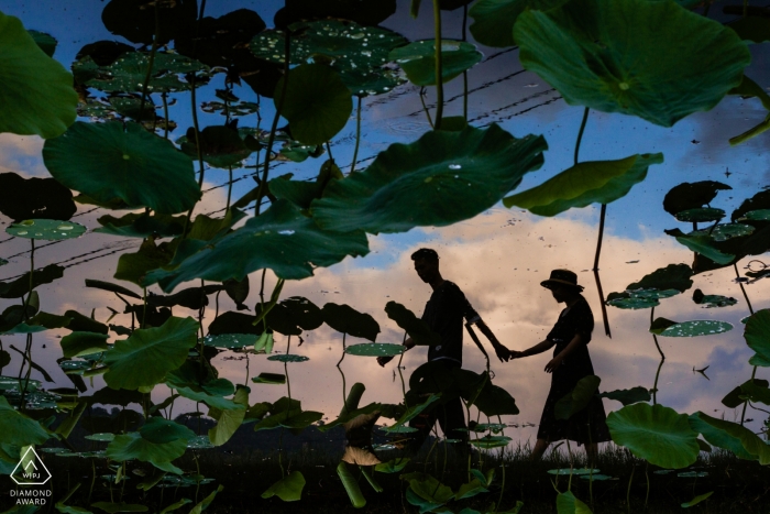 Fuijan, China - silhouettes of the happy couple walking hand in hand through a field were captured in this pre-wedding portrait session 