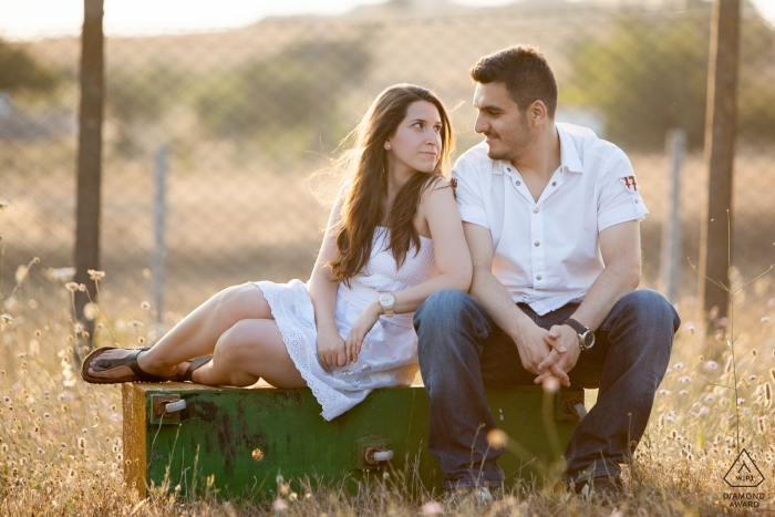 Photo by: <a href="https://www.wpja.com/photos/diamond-award-top-wedding-engagement-photographer/2476406">Erkin Agsaran - Kadikoy Istanbul Silivri, İstanbul Engagement Portrait of a couple sitting on a flipped-over metal box in front of a fence and looking at each other