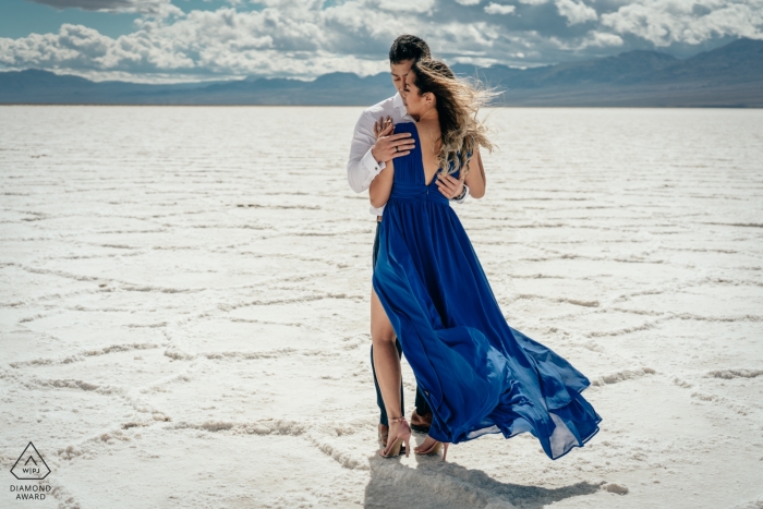 Death Valley engagement shoot takes place in the middle of a desert while mountains stand in the distance behind the embracing couple