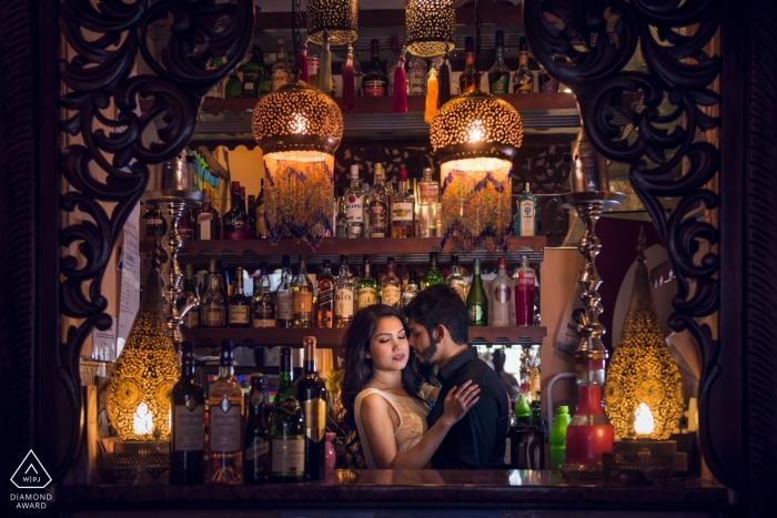 Bath, UK engagement photo session of a couple embracing in front of a well stocked bar