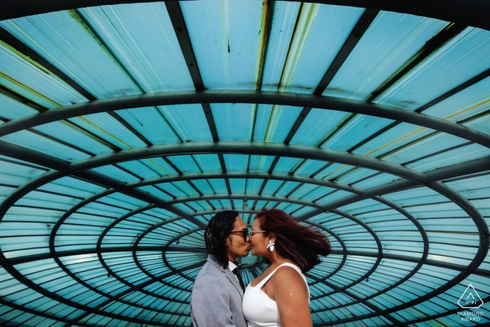 Un couple embrasse sous une fenêtre en spirale et un ciel bleu à Colombo cette séance photo de fiançailles par un photographe de mariage sri-lankais.