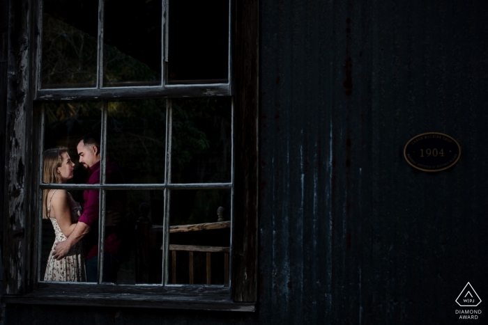 A man and woman can be seen holding one another through a window during their engagement session in Fort Myers by a Key West, FL photographer. A man and woman can be seen holding one another through a window during their engagement session in Fort Myers by a Key West, FL photographer.