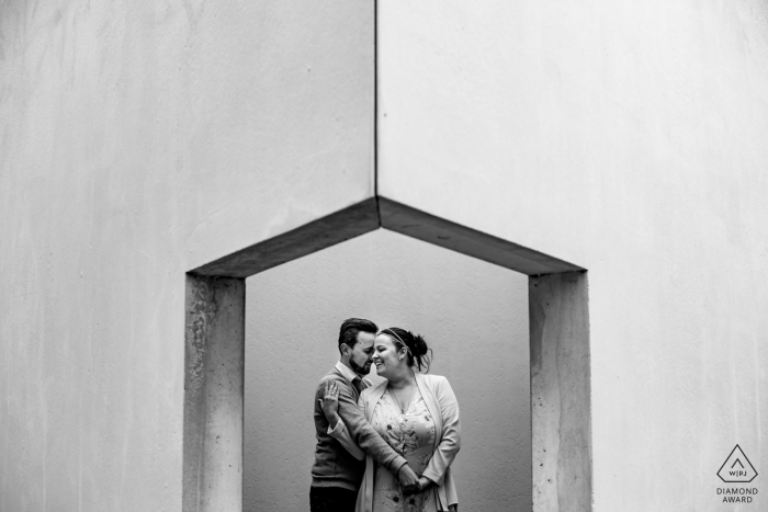 A couple holds hands as they stand beneath an archway in Middelheim in this black and white engagement photo by an Antwerpen, Flanders photographer.