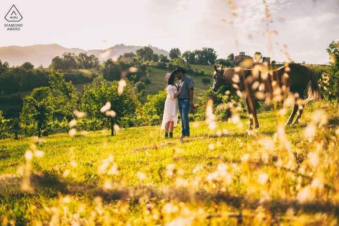 Una pareja se para con un caballo en un campo soleado en Alvito, Francia, en esta foto de compromiso de un fotógrafo de Lazio.