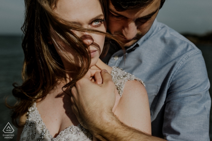 Santa Catarina, un couple à Paraia do Rosa, tient les mains au bord de l'eau dans ce portrait de mariage réalisé par un photographe du Rio Grande do Sul, au Brésil.