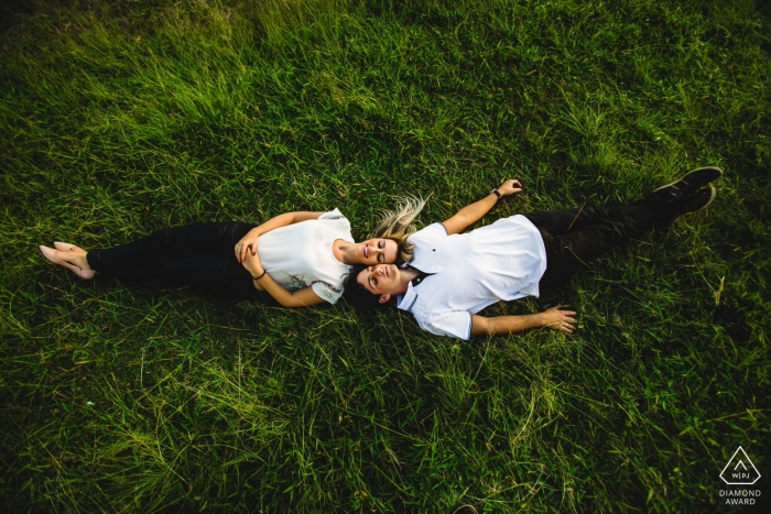 Photo by: <a href="https://www.wpja.com/photos/diamond-award-top-wedding-engagement-photographer/2496146">Vinicius Terror - Ouro Preto Minas Gerais A couple lays head to head together on the grass in Ouro Preto during their engagement photoshoot by a Minas Gerais, Brazil photographer.