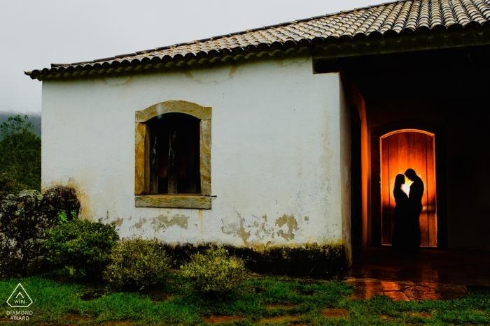 Um casal em Ouro Preto pode ser visto em pé dentro de uma casa nesta foto de noivado por um fotógrafo de Minas Gerais, Brasil.